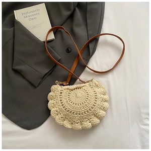 Close-up of cream crochet saddle bag with brown leather strap and gold hardware accents