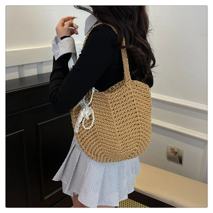 Detail of hand-woven khaki tote bag with lace and pearl pendant in French retro style