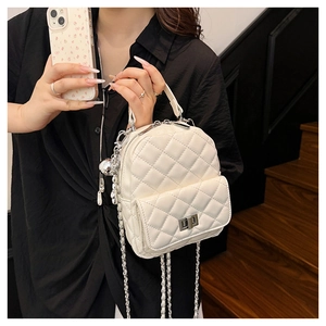 Close-up of white quilted mini backpack featuring metal twist lock and chain strap detail