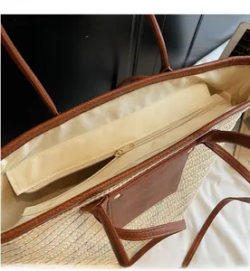 Detail view of smooth zipper closure and premium brown leather trim on woven tote bag