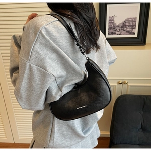 Detailed view of black pebbled leather crescent hobo bag worn over the shoulder