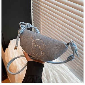 Détail du sac croissant en jean bleu clair avec broderie chien et bandoulière à nœud