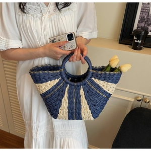 Detailed texture of blue and beige woven straw bag with gold thread and round handles