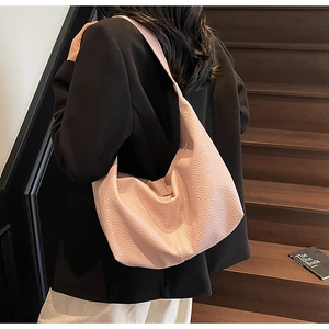 Detail of pink lychee grain hobo shoulder bag worn with a black blazer on stairs