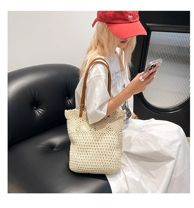Detail of cream woven tote featuring hollow petal knit patterns and brown leather straps