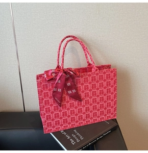 Detail of red bridal tote bag with woven Double Happiness pattern and silk bow ribbon
