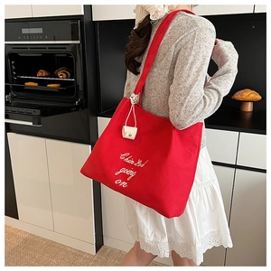 Détail du sac cabas en toile rouge avec lettrage blanc et mini pochette en cuir blanc