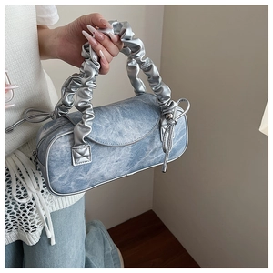 Dettaglio della borsa a bauletto in denim azzurro con manico metallico argento
