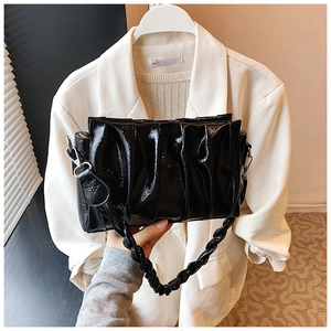 Close-up of black pleated cloud bag featuring glossy texture and woven shoulder strap