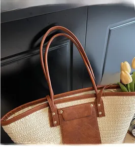 Detail of durable leather handles and woven texture on a large straw tote bag