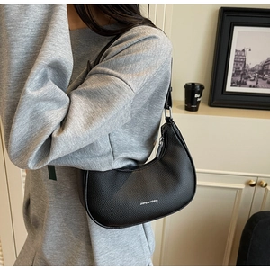 Close-up of black lychee grain leather crescent bag with white printed brand logo