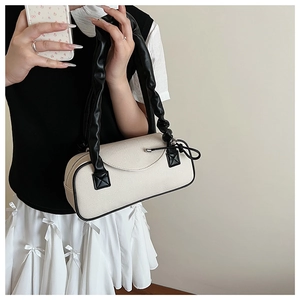 Dettaglio della borsa a spalla in tessuto bianco crema con finiture in pelle nera