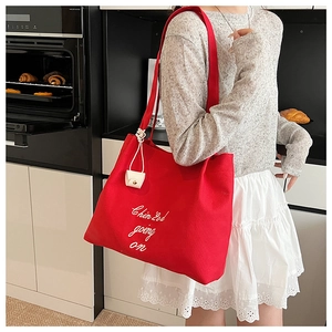 Détail du grand sac cabas en toile rouge avec imprimé blanc et pendentif en cuir