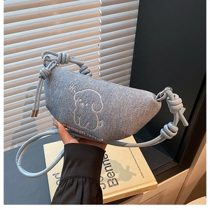 Détail du sac croissant en denim bleu clair avec broderie chiot et bandoulière à nœuds design