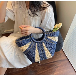 Detail of blue and white woven straw handbag with gold thread on the handles