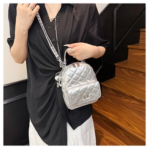 Close-up of silver quilted mini backpack with metal chain strap and twist-lock detail