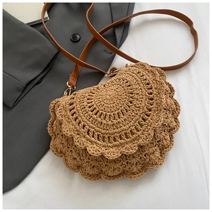 Close-up of woven saddle bag with shell-edged details and brown leather strap