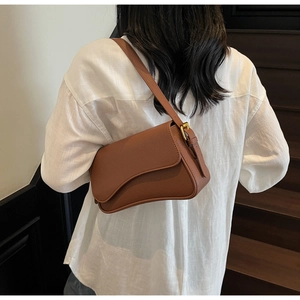 Detail of brown lychee grain leather crossbody bag with golden buckle and sleek design