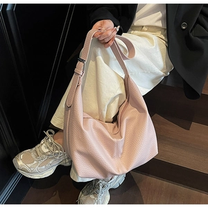 Pink lychee texture crossbody bag with slouchy crescent design shown in a lifestyle setting