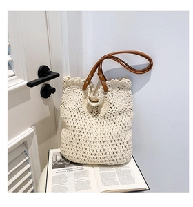 Detail of woven knit tote bag showing textured crochet pattern and brown leather handles
