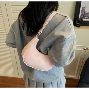 Adjustable light pink lychee leather crescent bag shown on shoulder in a lifestyle setting