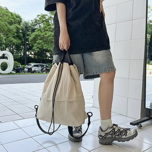 Detail der cremeweißen Nylon-Zugbandtasche mit schwarzen Kordeln und verstellbaren Gurten