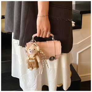 Detailed shot of a pink cylinder bag with a cute plush bear charm on a staircase