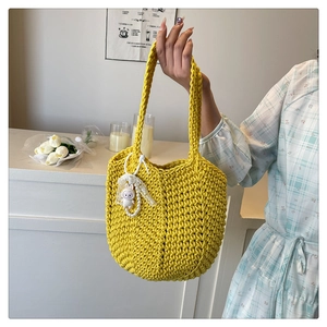 Detail of yellow woven tote bag featuring a cute bunny pendant and handmade texture
