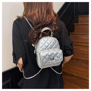 Detailed view of silver quilted mini backpack with metal chain straps on a model