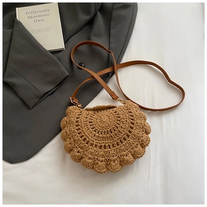 Close-up of a woven straw saddle bag with leather strap and golden metal hardware