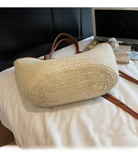 Detail of cream woven straw tote bag with brown leather handles on a home desk