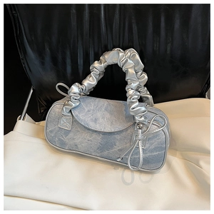 Dettaglio borsa a cuscino in denim blu con manico argento arricciato e fiocco laterale