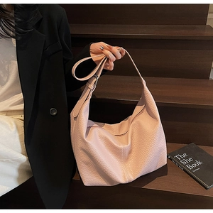 Detail of light pink pebbled leather hobo bag with soft drape on a minimalist background