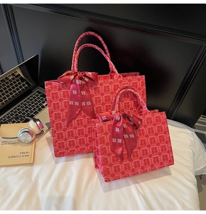 Detail of red wedding tote bags featuring Xi character jacquard and satin bows