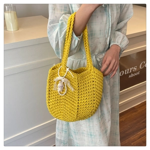 Detailed knit texture of a yellow woven tote bag with a cute rabbit and pearl charm