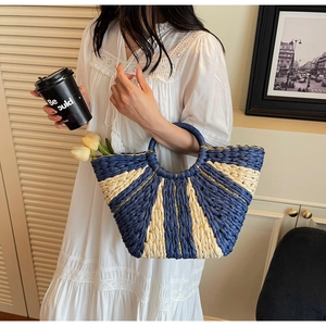 Detail of blue and white woven straw bag with gold thread accents and round handle