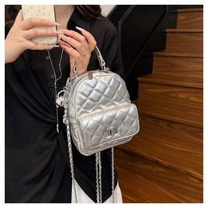 Silver quilted mini backpack with metallic finish and metal chain straps on stairs