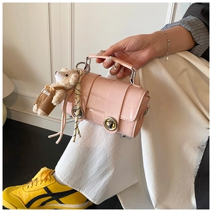 Detail of pink patent leather pillow bag with metal lock and cute teddy bear charm