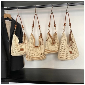 Detail showing beige woven tote with brown leather strap and wooden bead accents