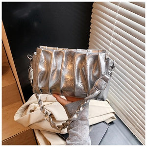 Detail of silver pleated cloud bag featuring metallic texture and woven shoulder strap