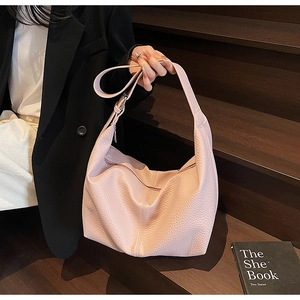 Pink lychee-textured hobo bag with wide shoulder strap showing soft slouchy leather detail