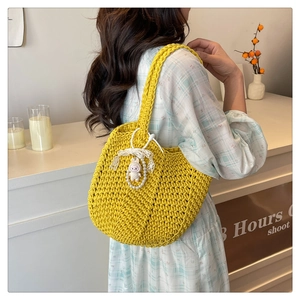 Detailed view of yellow woven tote bag with a cute white rabbit charm and lace trim