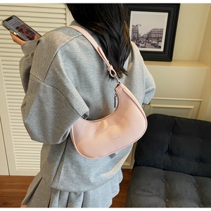 Detailed view of pink pebble leather half-moon shoulder bag with sleek zip top closure