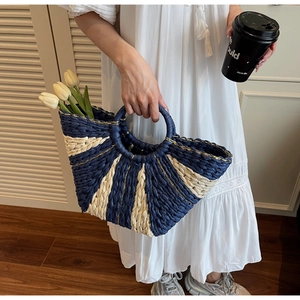 Detail shot of the contrast woven straw tote bag with navy and beige radial patterns