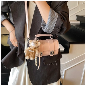 Pink patent leather crossbody bag with silver ring lock and teddy bear charm on model