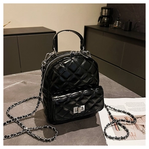 Detailed view of black quilted faux leather mini backpack with chain strap on marble