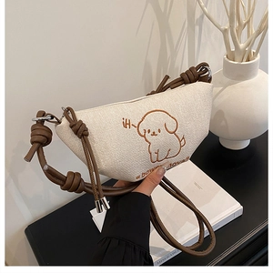 Détail de la broderie chiot et bandoulière en cuir noué sur sac besace en toile