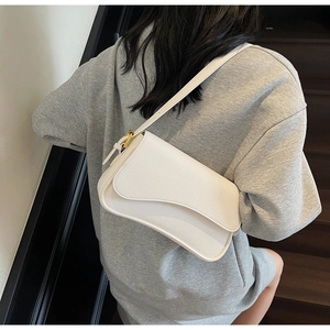 Close-up of a white lychee grain leather underarm bag with a unique wavy flap edge design