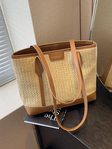 Large woven straw tote bag with brown leather trim and shoulder straps for women