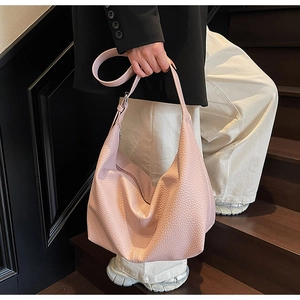 Detailed texture of pink pebbled leather on a large minimalist half-moon crossbody bag